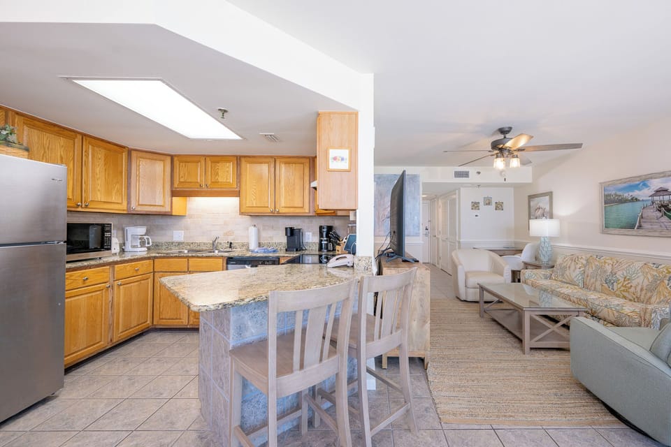 The inviting kitchen features wooden cabinetry, granite countertops, and a cozy seating area with a floral-patterned sofa