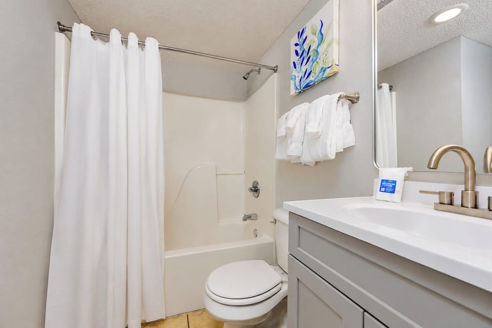 his bathroom features a design with a spacious vanity, fresh towels, and a shower-tub combination for your convenience