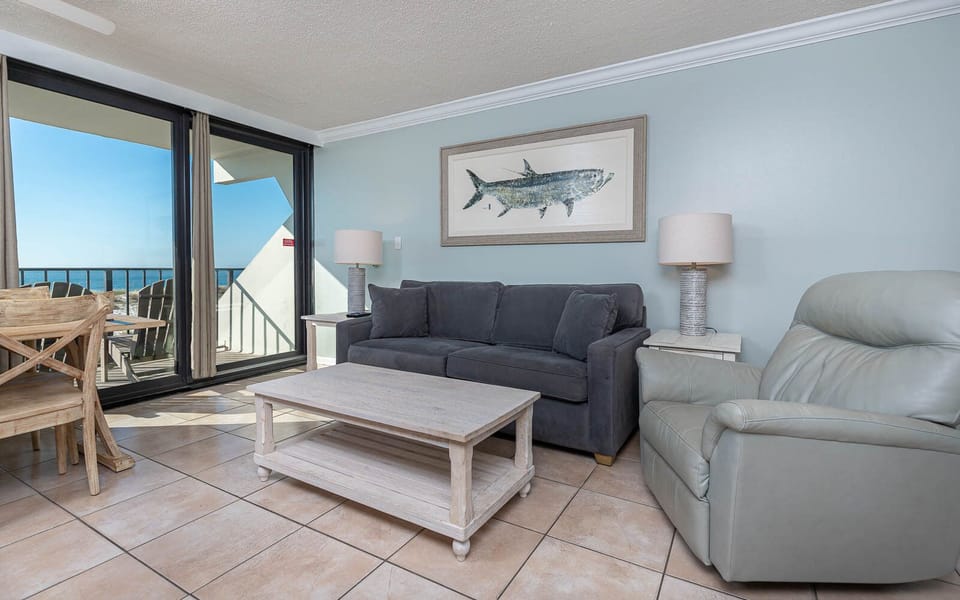 This inviting seating area features a comfortable couch, stylish decor, and stunning beachfront views from the large windows