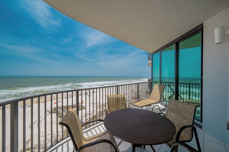 Relax on the balcony with seating, enjoying views of the beach and gentle waves in the distance