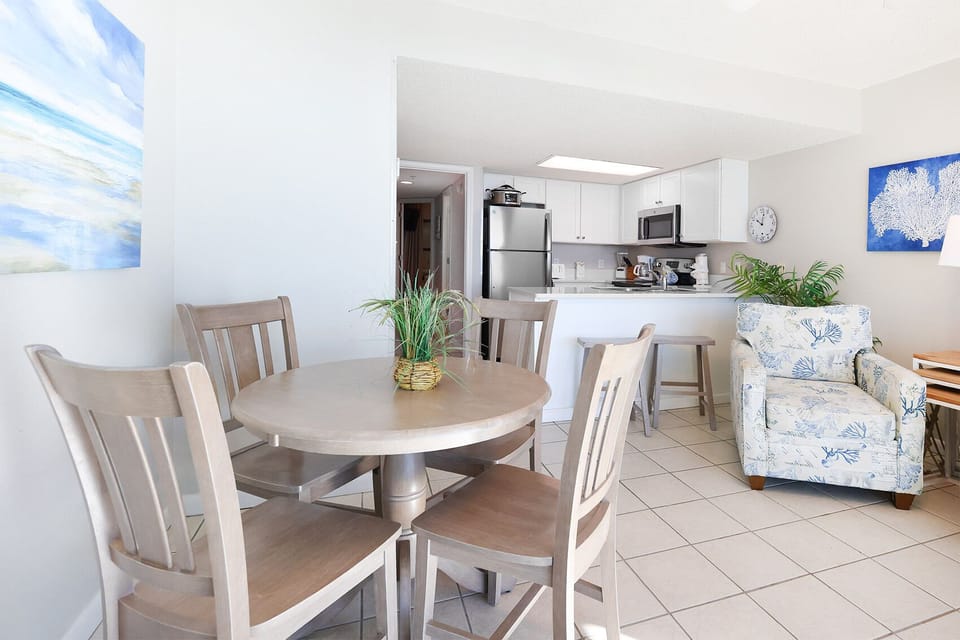 Dine comfortably at the round table, surrounded by light decor and a view into the functional kitchen area