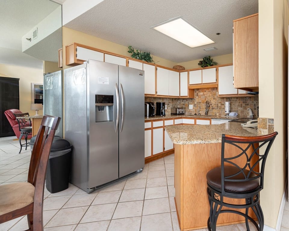 Prepare meals in the spacious kitchen featuring stainless and white appliances and a convenient breakfast bar