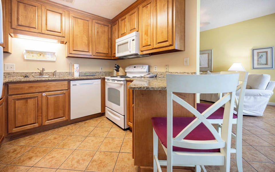 Prepare meals in the warm wood kitchen, featuring granite countertops and a convenient breakfast bar
