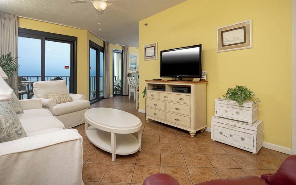 Relax in the cozy living area featuring comfortable seating, a flat-screen TV, and beach balcony access