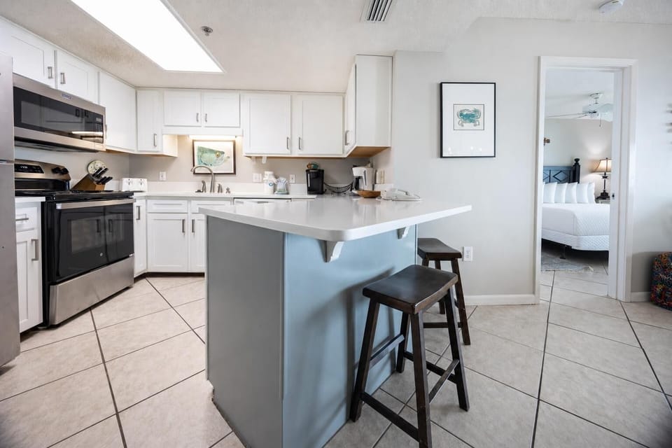 Kitchen features a breakfast bar with seating, white cabinetry, and a coffee corner with Keurig and coffee maker