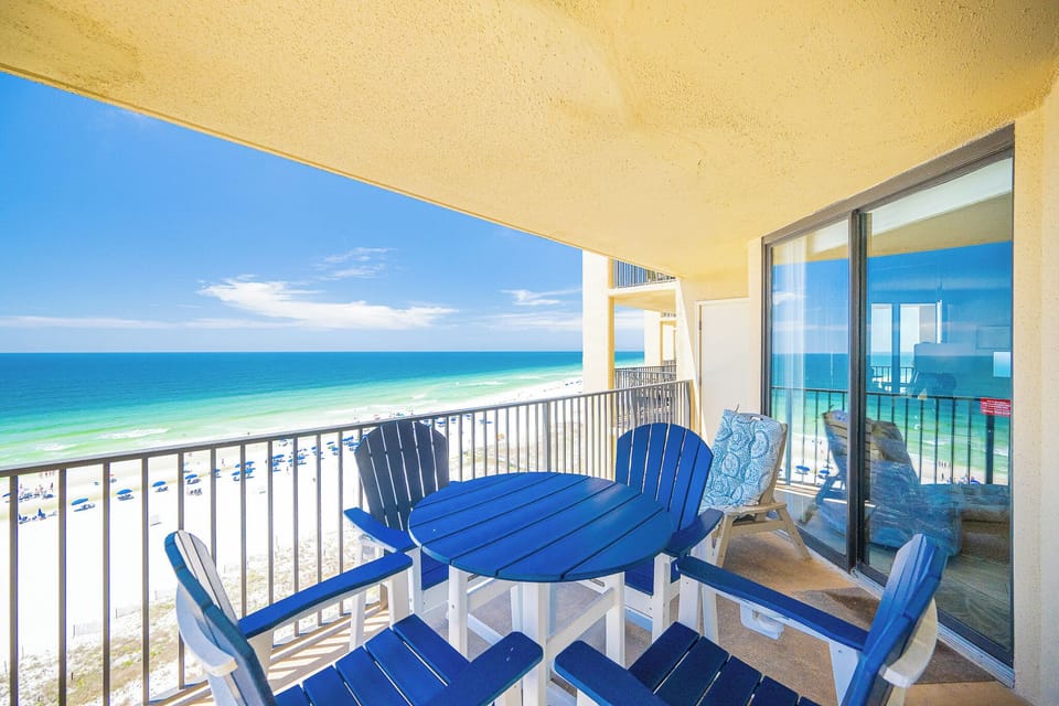 Enjoy a relaxing outdoor dining experience on the balcony with a stunning view of the beach and clear blue skies
