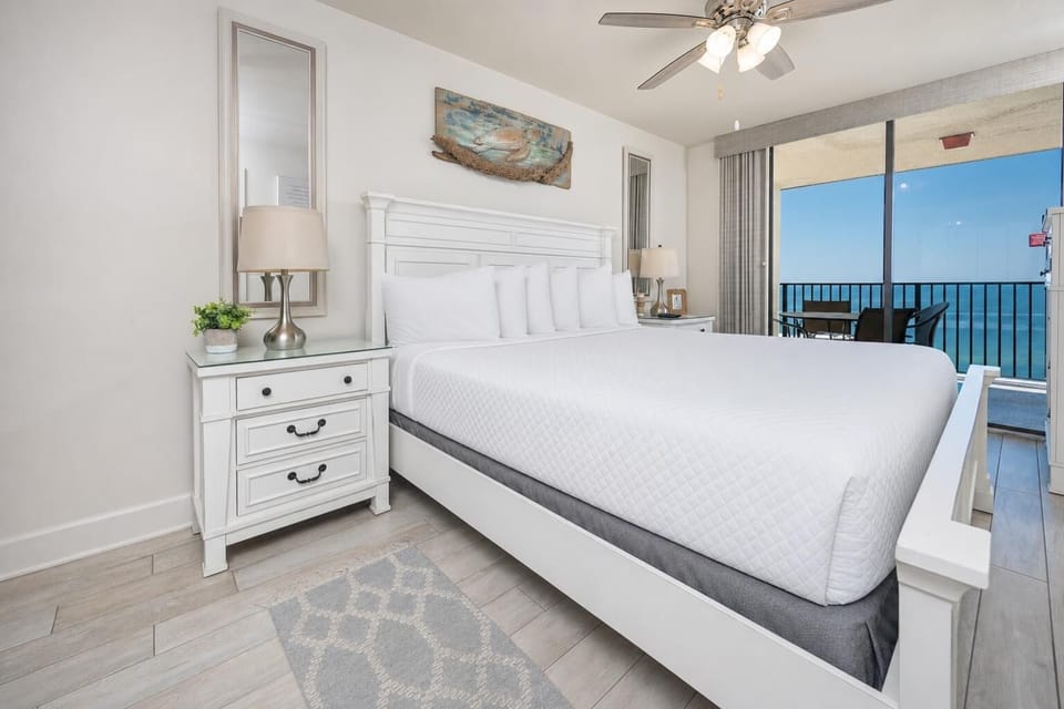 Master suite featuring a king bed, stylish nightstands, and a balcony view overlooking the beach