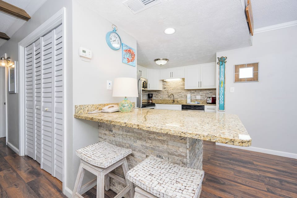 This inviting kitchen features stylish cabinetry, a granite countertop, and seating for a relaxed dining experience