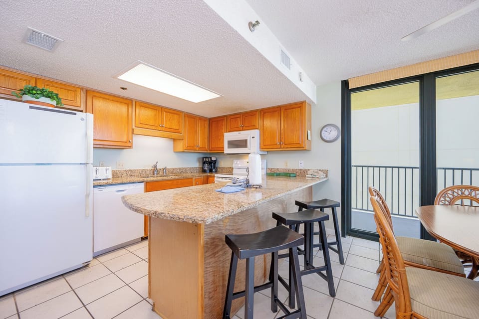 Kitchen featuring wooden cabinets, granite countertops, and a breakfast bar with seating for four, perfect for casual dining