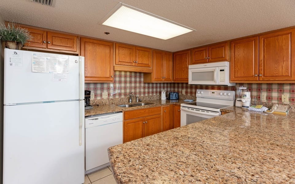 The modern kitchen features warm wooden cabinetry, granite countertops, and a convenient breakfast bar for casual dining