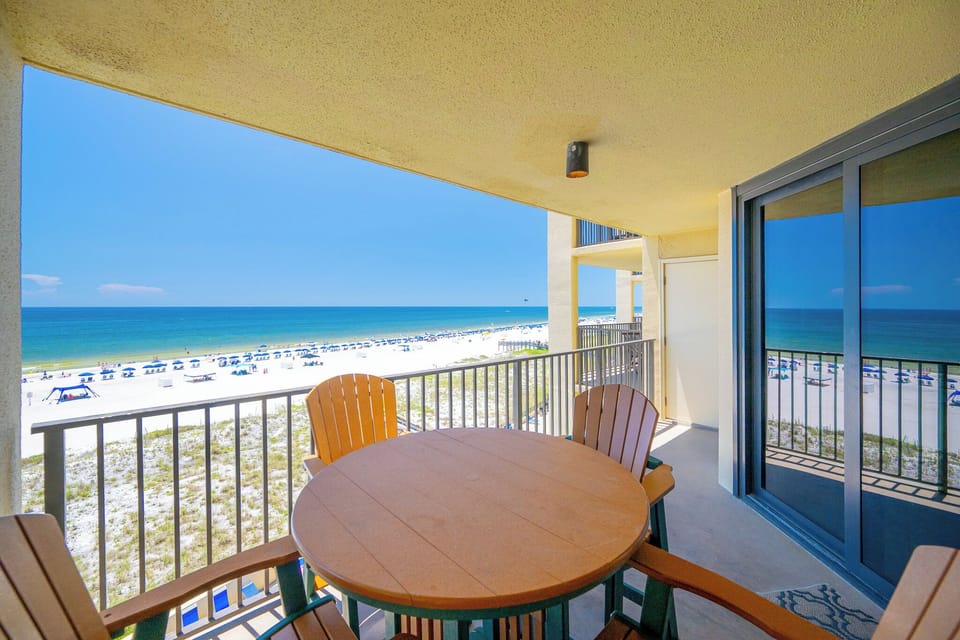 Enjoy a serene beachfront view from the balcony, overlooking white sand and colorful umbrellas lining the shore