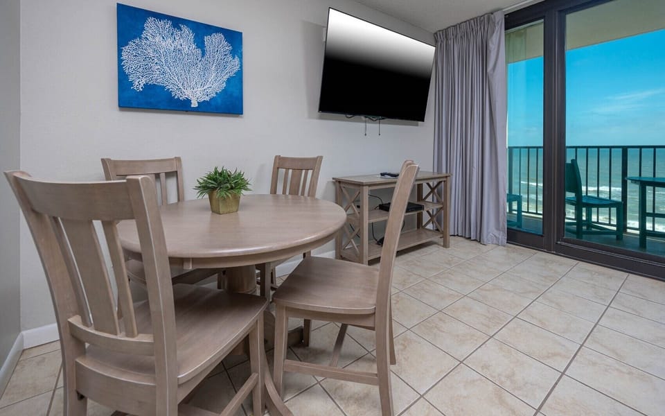Gather around the dining table for meals or family game night enjoying the beachfront balcony view