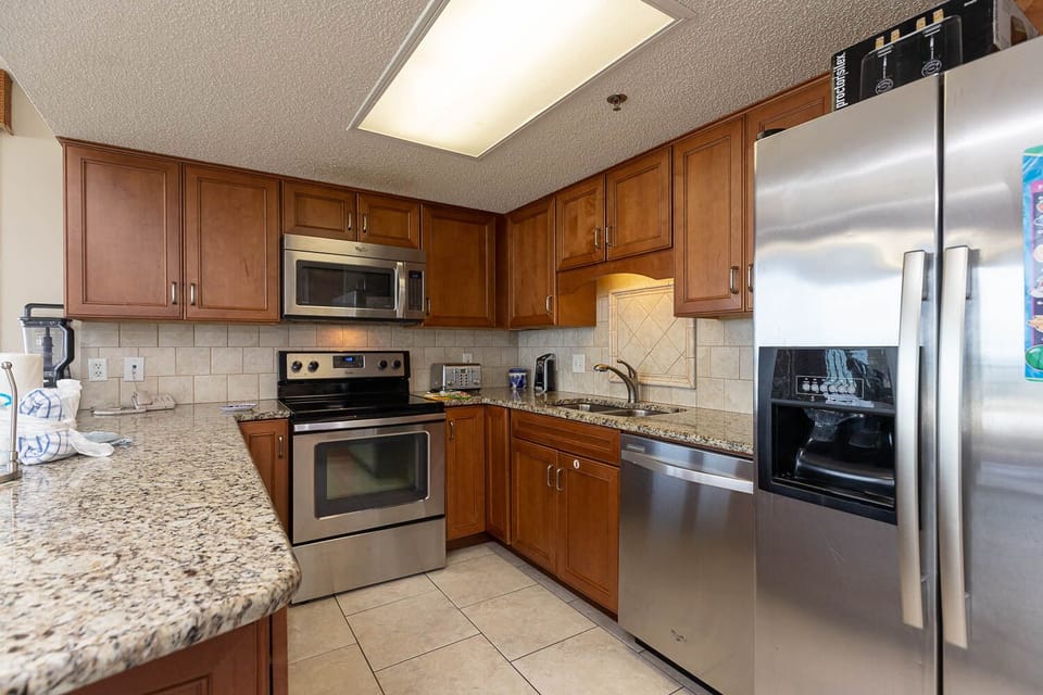 Warm wooden cabinets complement the granite countertops in this modern kitchen, featuring stainless appliances