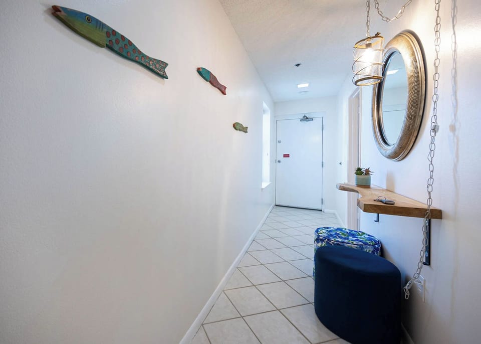 Enter a welcoming hallway adorned with colorful fish decor, a stylish mirror, and seating for a relaxed arrival