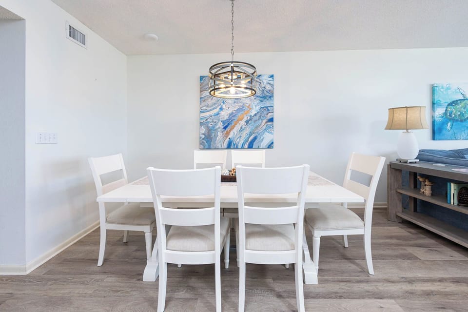 Dine comfortably at the spacious table surrounded by vibrant artwork and soft lighting for a welcoming atmosphere