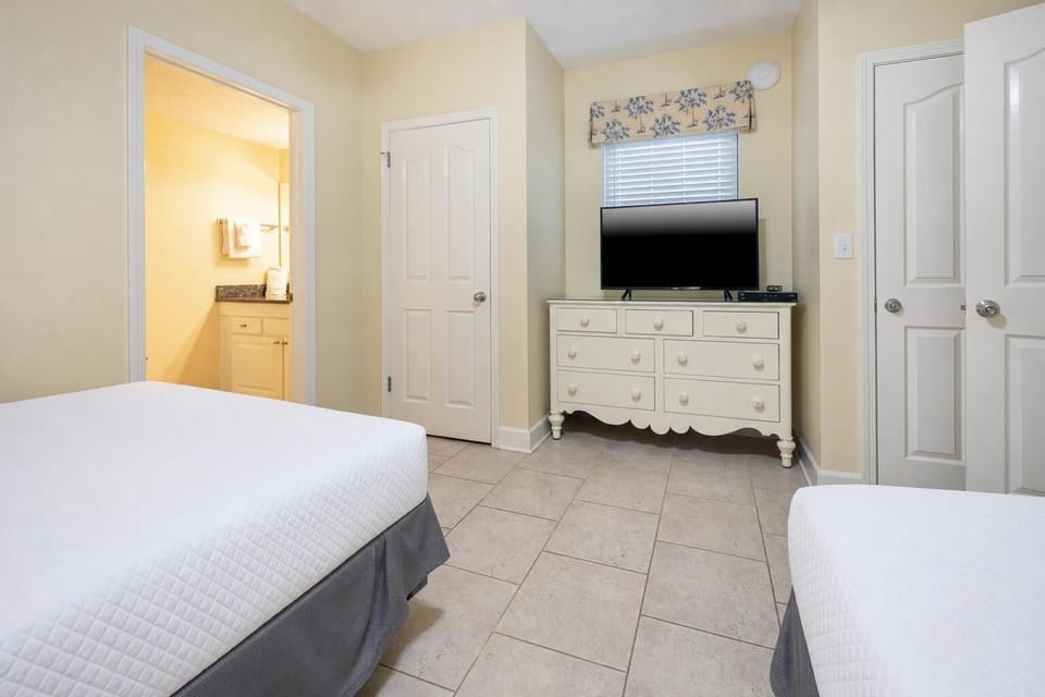 Relax in the comfortable guest bedroom featuring two double beds, a TV, and easy access to the adjoining bathroom