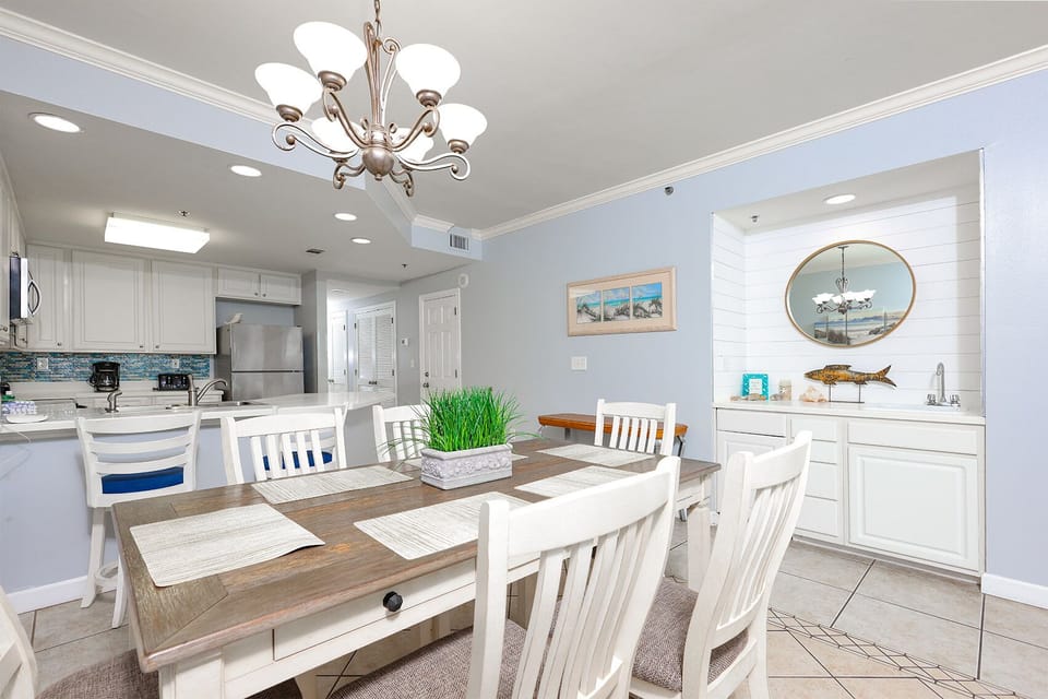 This dining area features a rustic table, white chairs, and a stylish wet bar, perfect for entertaining with a beach view