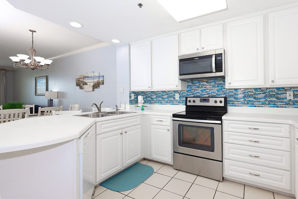 This kitchen features stainless appliances, bright blue tile accents, and a spacious layout ideal for meal preparation