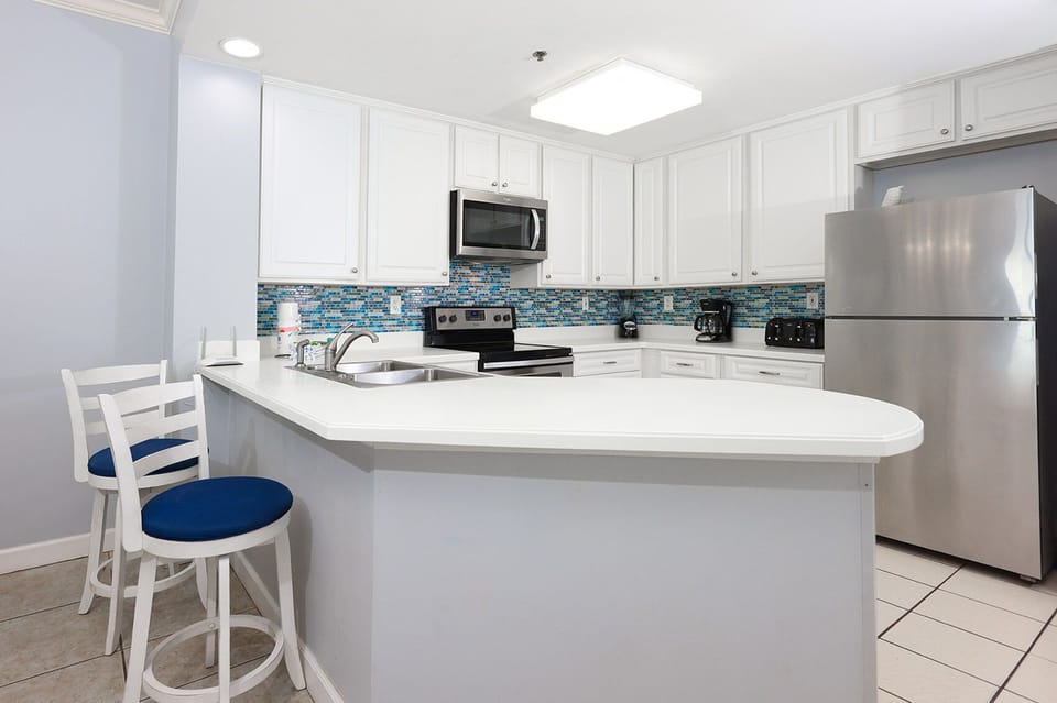 The kitchen features white cabinets, stainless appliances, and a vibrant tile backsplash, perfect for culinary adventures