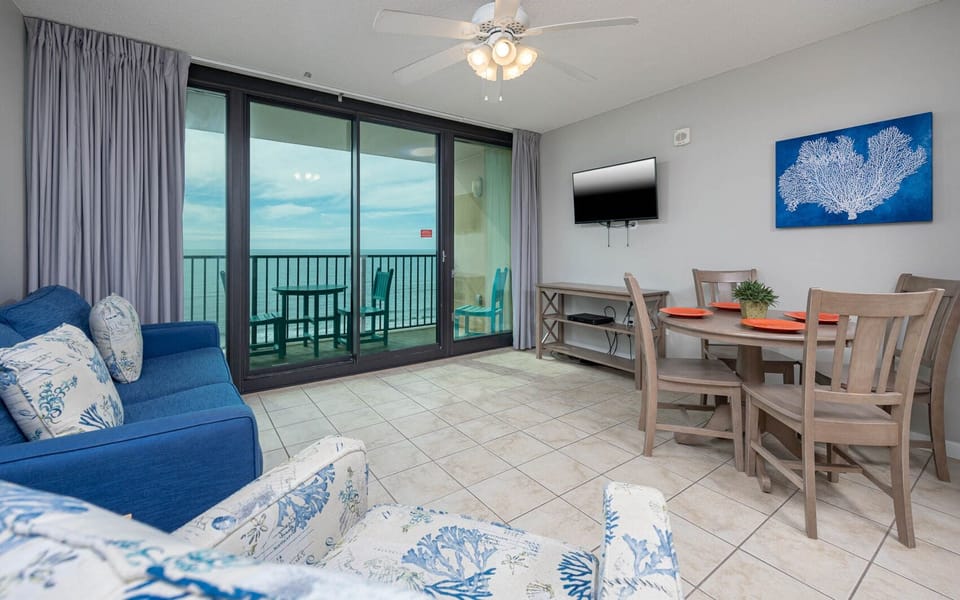 Relax in this inviting living space featuring a cozy sofa with queen sleeper, dining area, and beachfront balcony view