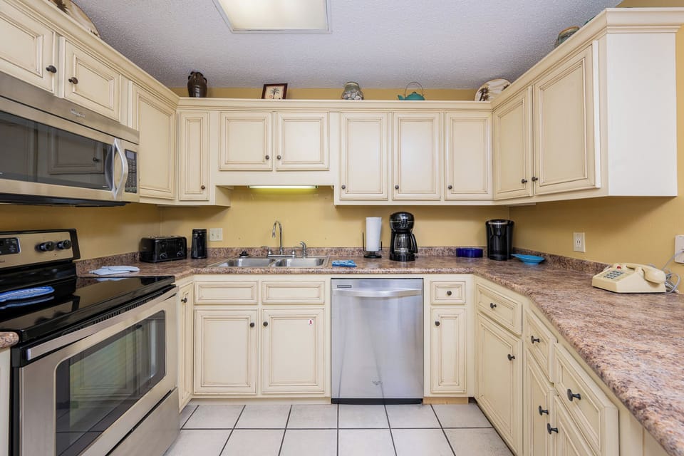 Prepare meals in the inviting kitchen featuring ample counter space, stainless appliances, and cheerful decor