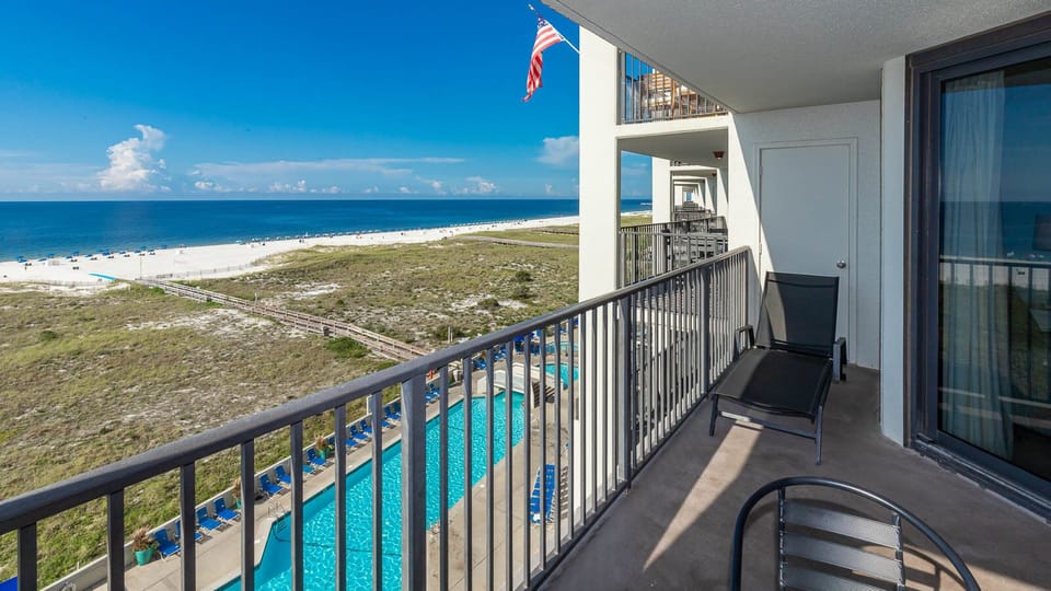 Balcony view showcasing the inviting pool area and the expansive beach with vibrant blue waters and white sand