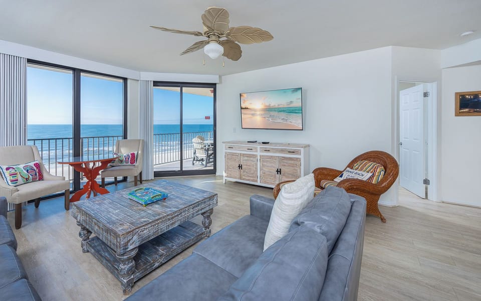 Unwind in the inviting living area, featuring a cozy couch with queen sleeper, vibrant decor, and beachfront views