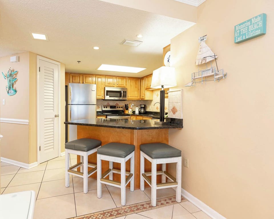Modern kitchen area featuring wooden cabinetry, a breakfast bar with seating, and decorative beach accents