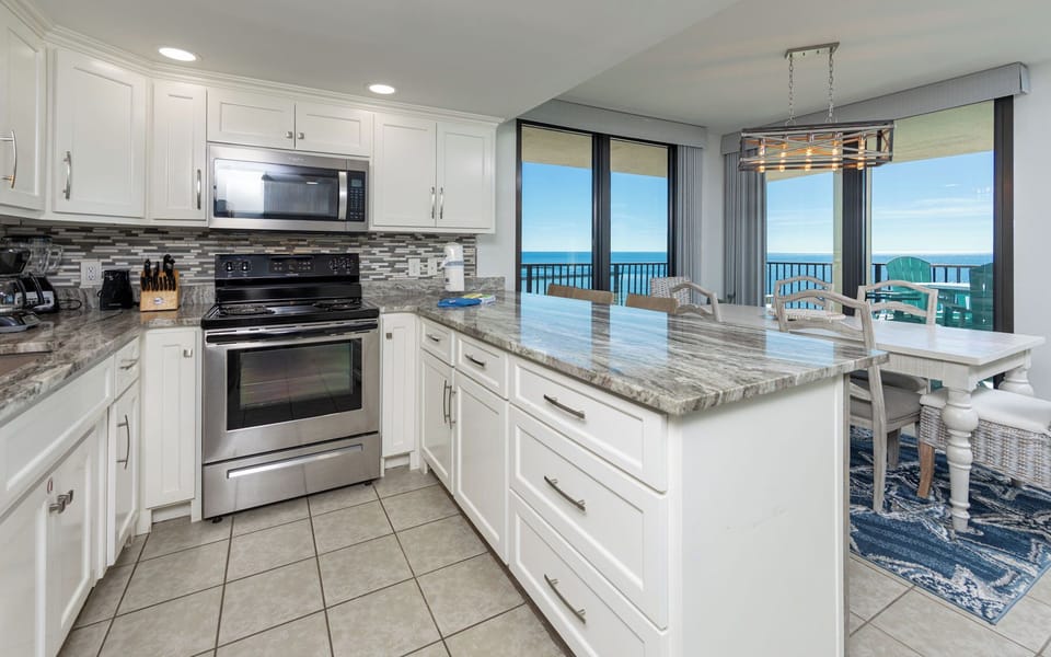 Enjoy cooking in this stylish kitchen, featuring sleek counters, stainless appliances, and white cabinetry