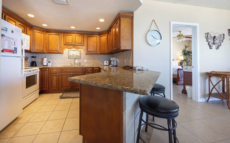 Cook and gather in the kitchen featuring rich wood cabinetry, granite countertops, and seating at the bar