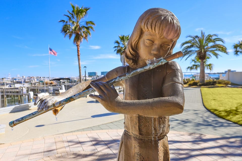 Discover a charming waterfront view with a playful statue and palm trees, perfect for a relaxing getaway