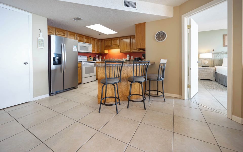 The fully-equipped kitchen features warm wooden cabinetry and a breakfast bar with seating