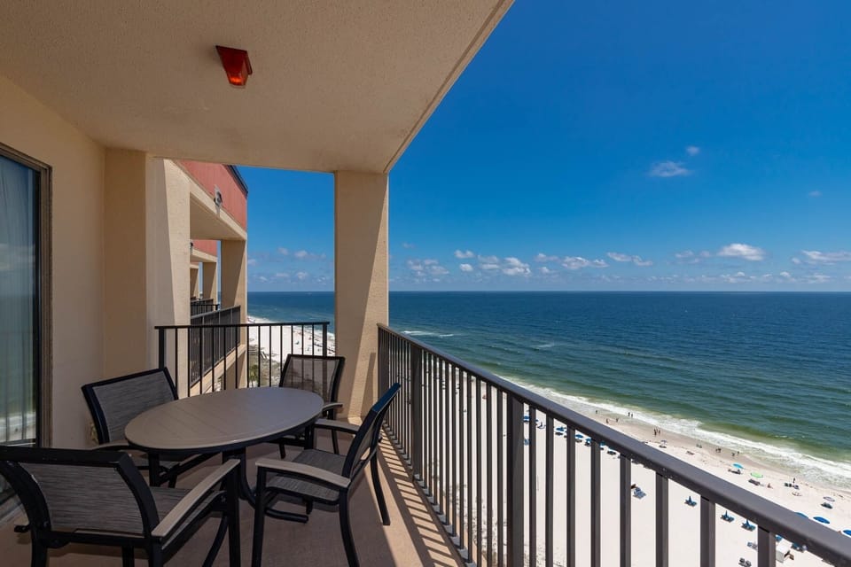 Enjoy a relaxing moment on the balcony with a table and chairs, overlooking the beach and vibrant blue waters