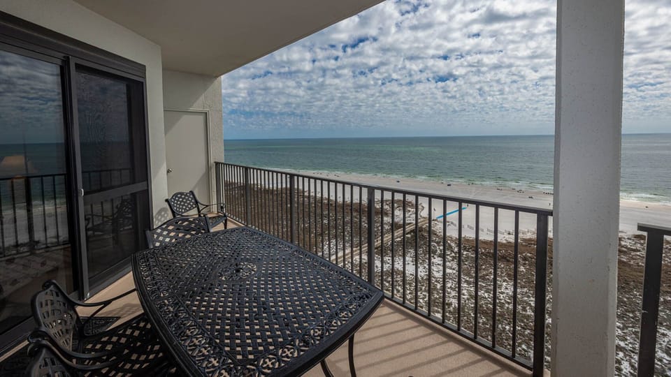 Balcony with a wrought-iron table and chairs offers a serene view of the beach and tranquil gulf waters