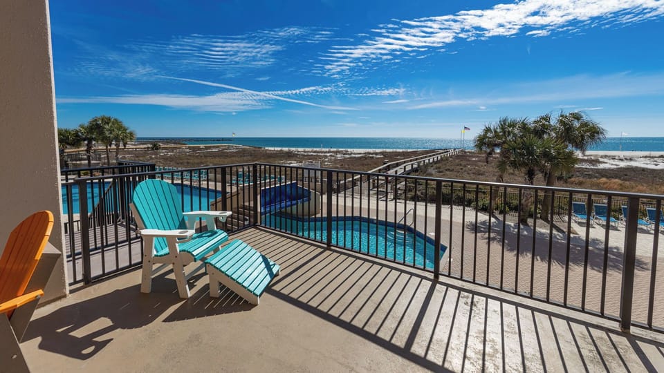 Relax in colorful chairs on the extended balcony, overlooking the pool and a scenic view of the coastline
