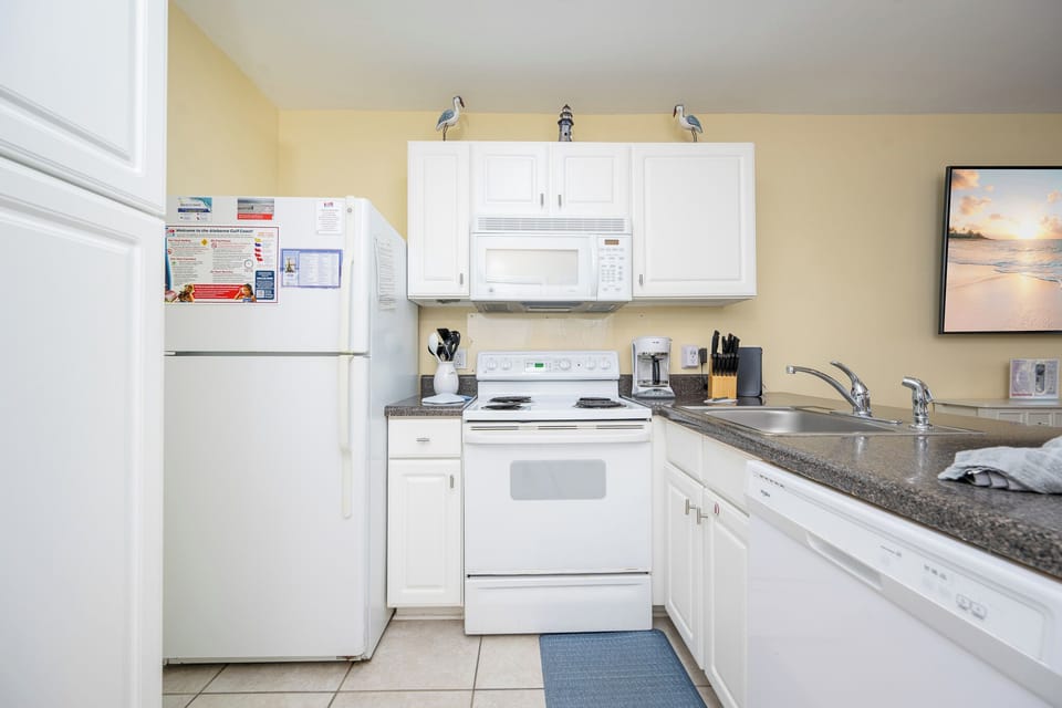 White cabinets brighten the kitchen where you prepare meals and brew coffee before heading to the coast