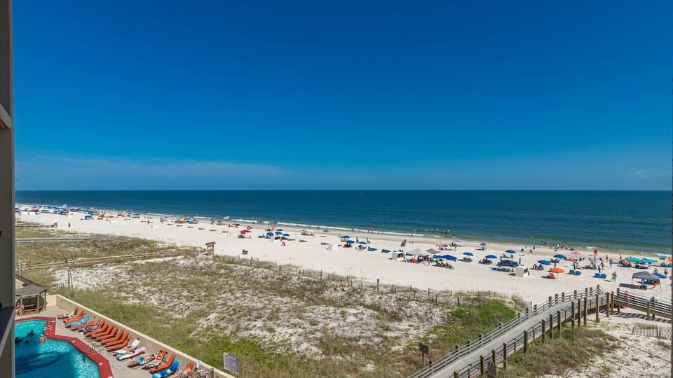 A vibrant view showcases the beach front with colorful umbrellas and sunbathers against a backdrop of clear blue skies