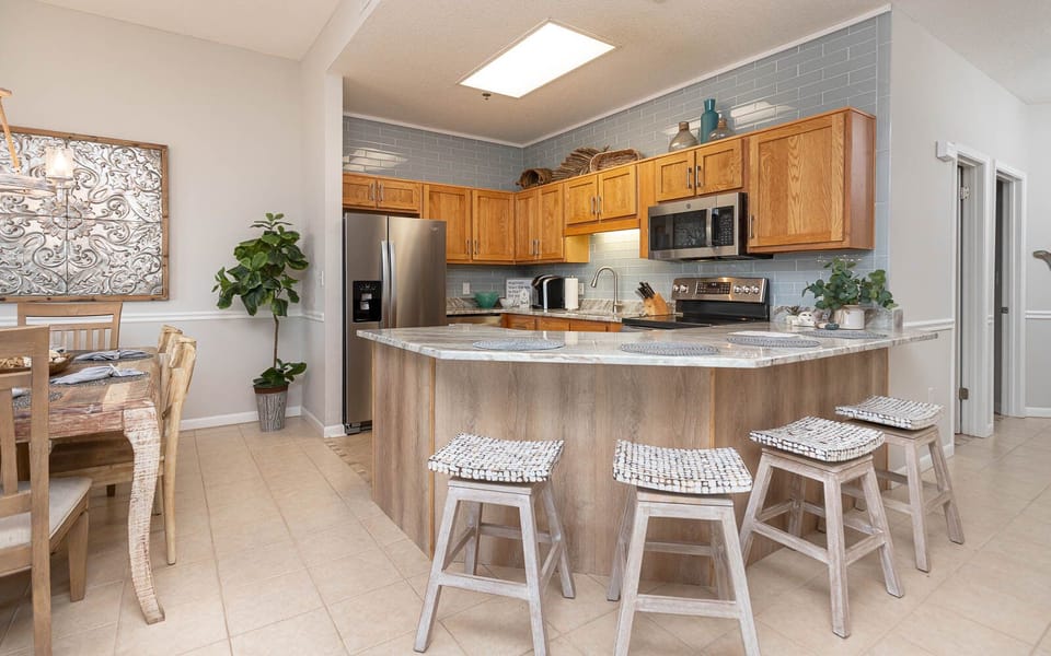 Bright kitchen features wood cabinetry, a marbled breakfast bar, stylish backsplash, and Keurig coffee corner