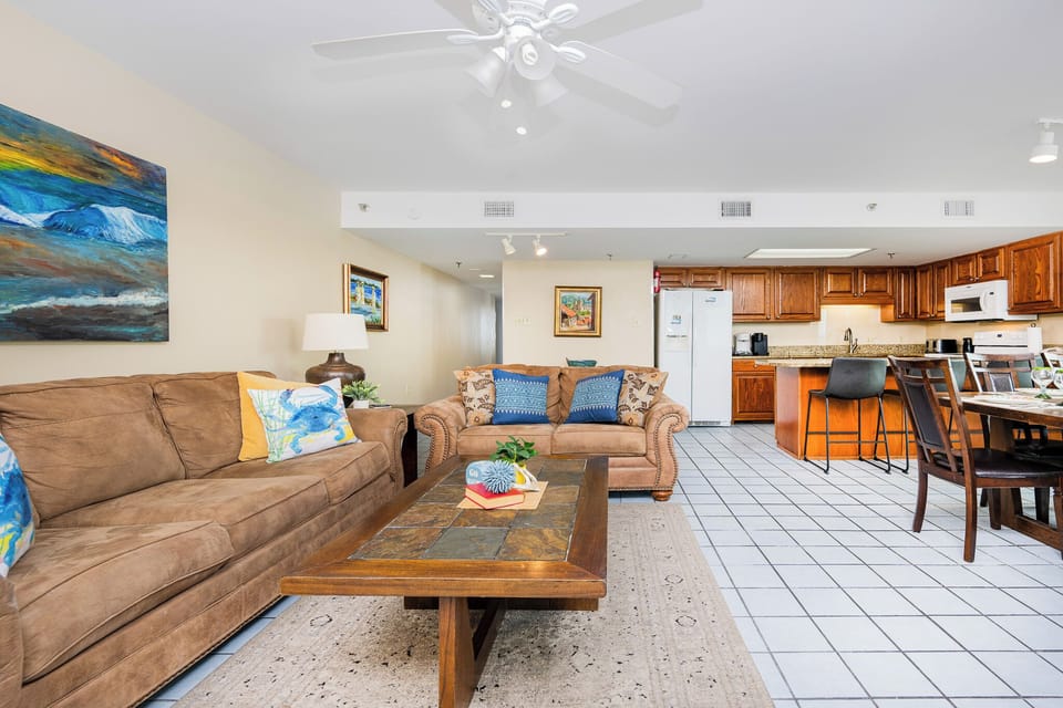 Living area featuring a cozy sofa, a wooden coffee table, and a view of the kitchen with wooden cabinetry
