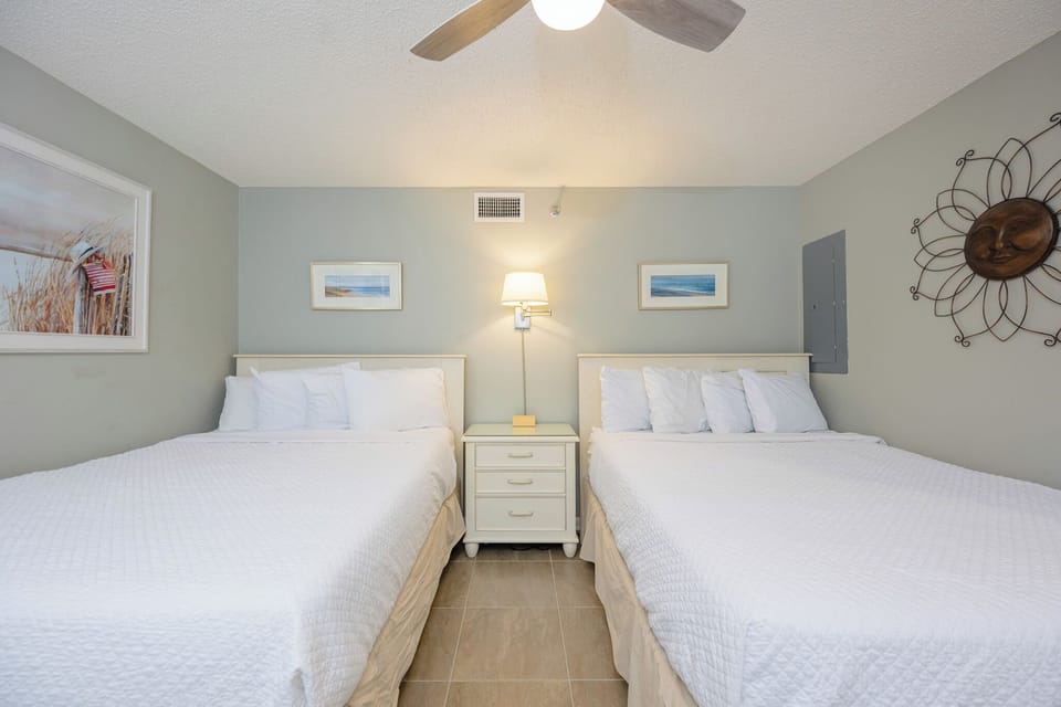 Relax in this inviting guest bedroom with two queen beds, soft linens, and beach decor for a restful stay