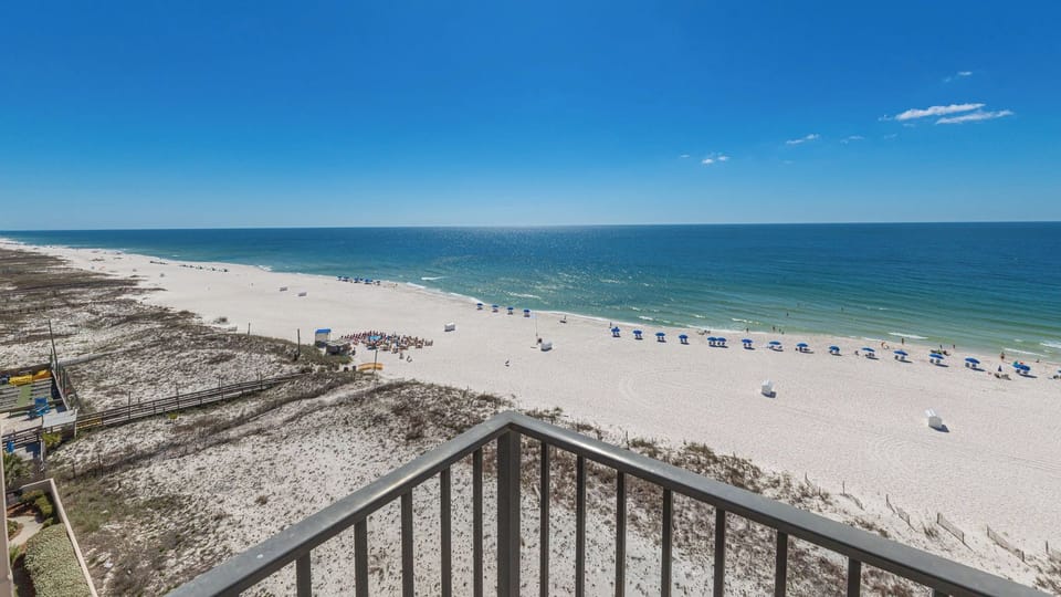 Your balcony invites you to watch sunlight shimmer on gentle waves stretching along the bright coastline