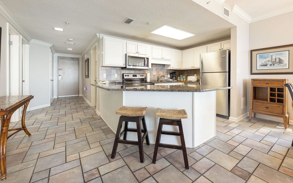 Granite breakfast bar invites you to unwind with morning coffee or casual snacks in the kitchen