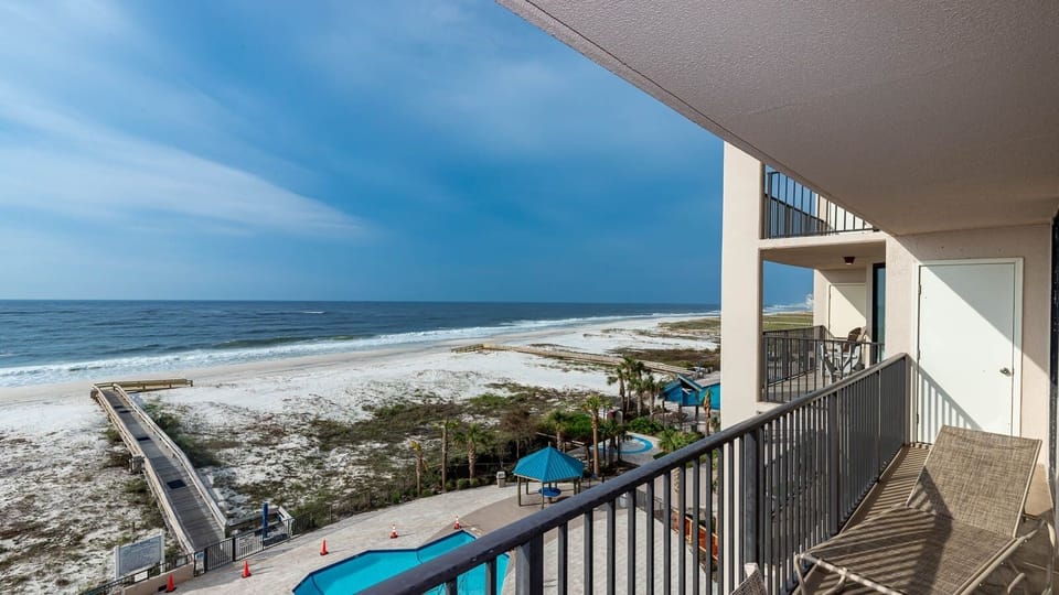 Enjoy the calming view of the waves from your balcony, with the pool and palm trees below