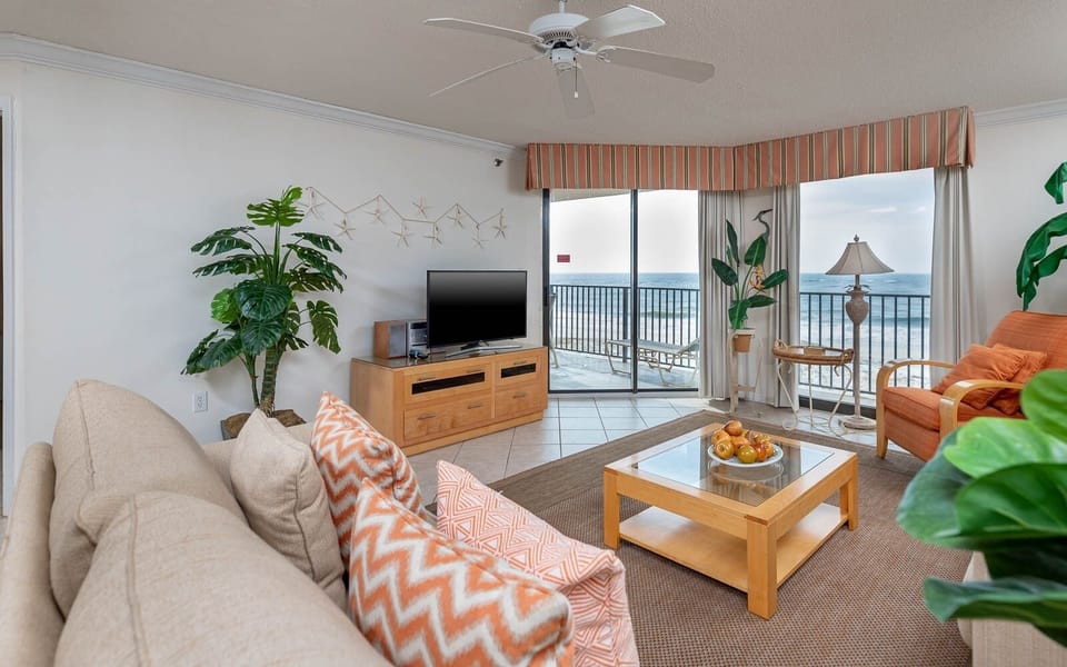 Relax in the living area with a TV, tropical plants, and easy access to the balcony for fresh gulf air and beachfront views