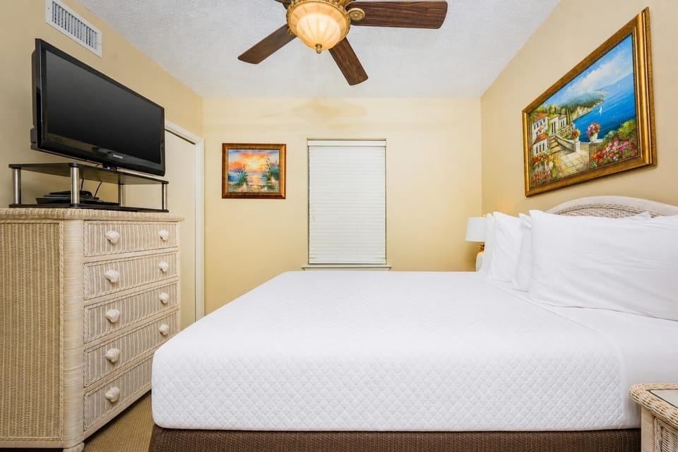 Inviting guest bedroom with a plush queen bed, a TV, and coastal artwork that adds charm to your stay