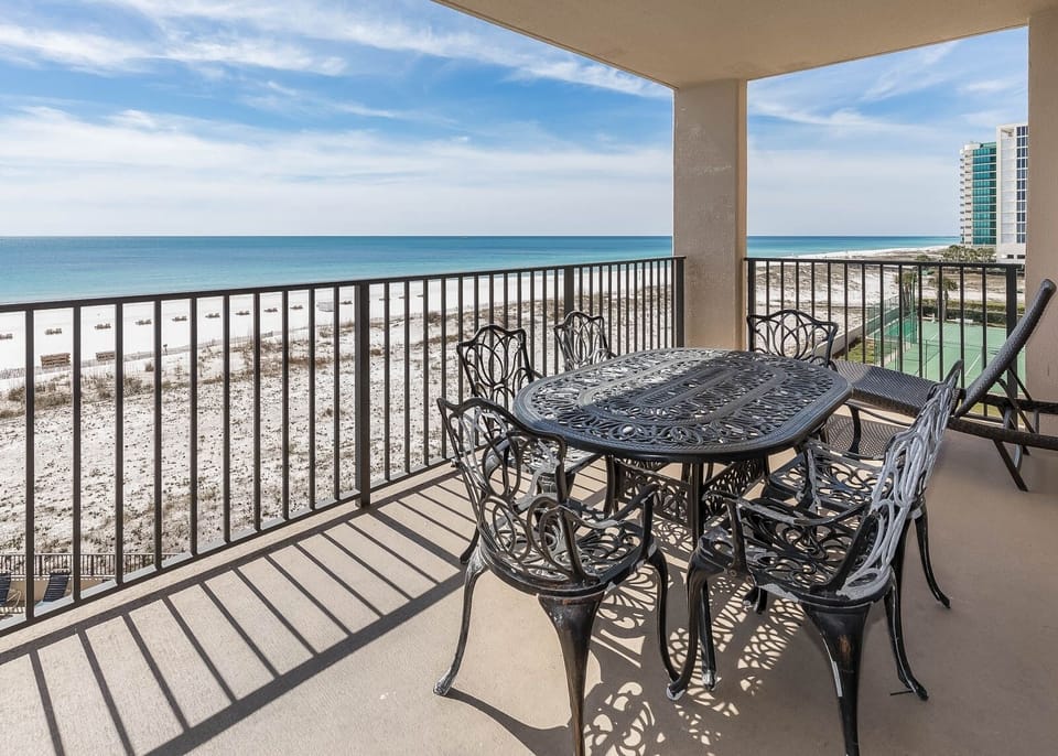 Dine al fresco at the elegant table, enjoying refreshing breezes and stunning beach views of the tranquil waters