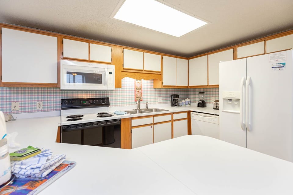 Cook and gather in this functional kitchen, featuring ample counter space, white appliances, and cheerful decor