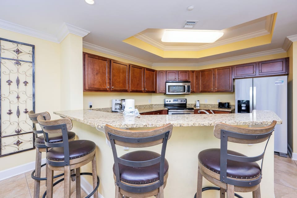This kitchen features rich wood cabinetry, granite countertops, stainless appliances, and a convenient Keurig coffee maker