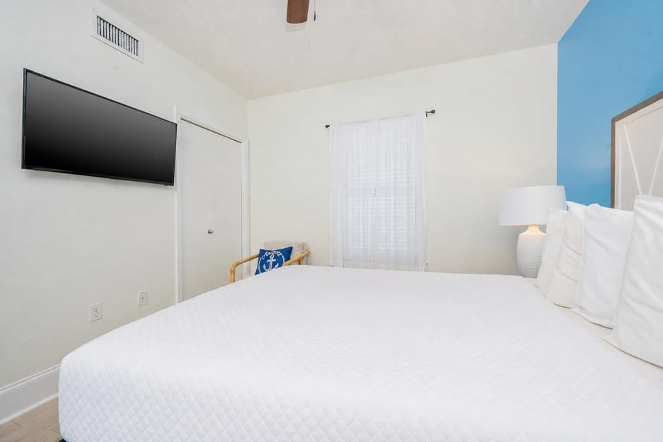 Relax in the guest bedroom featuring a queen bed, a cozy chair, and a large TV for your entertainment