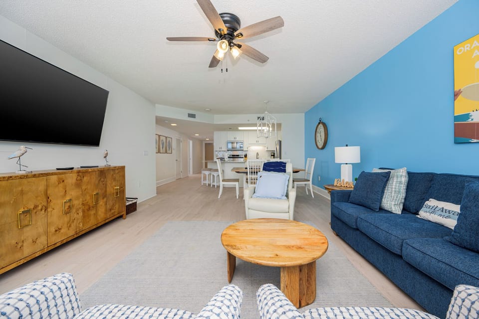 Relax in the inviting living area with a large TV, sofa with queen sleeper, and vibrant blue accents for a cheerful vibe